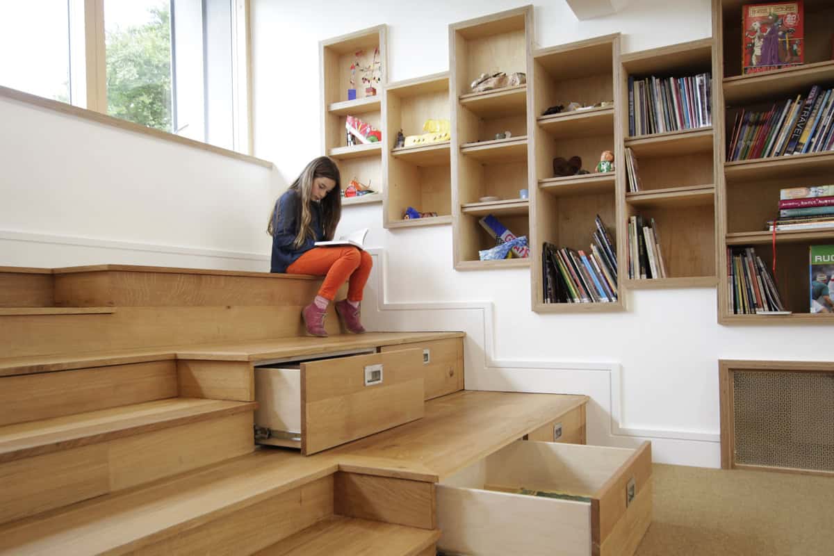 Beaudesert Park School Library child reading on stepped timber floor with storage drawers and shelving